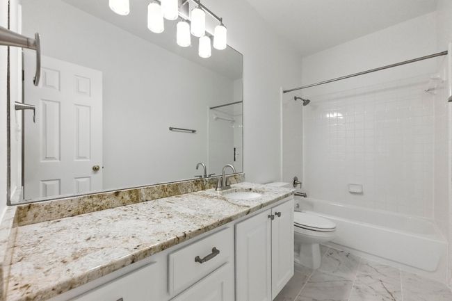 Bathroom featuring granite vanity, bathtub / shower combination, and new tile flooring | Image 27