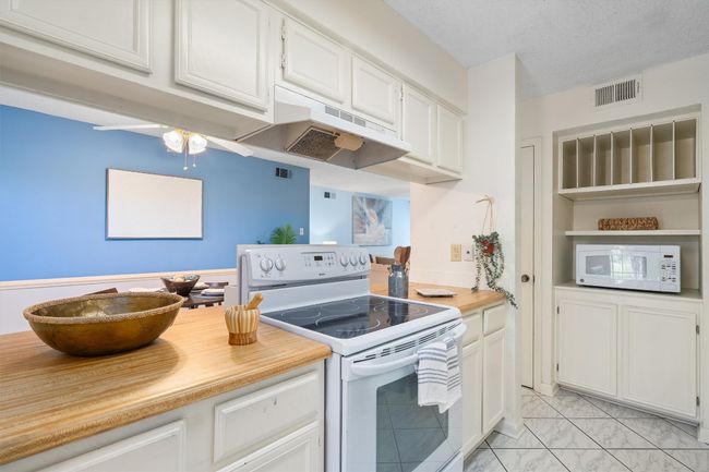 Kitchen featuring white cabinets, light countertops, white appliances, under cabinet range hood, and marble finish floor | Image 15