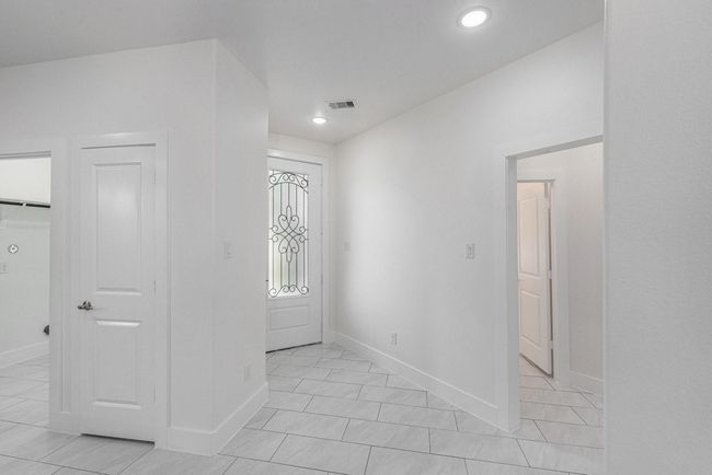 Bright entryway featuring white walls and tile flooring, with elegant decorative door glass and modern recessed lighting. | Image 5