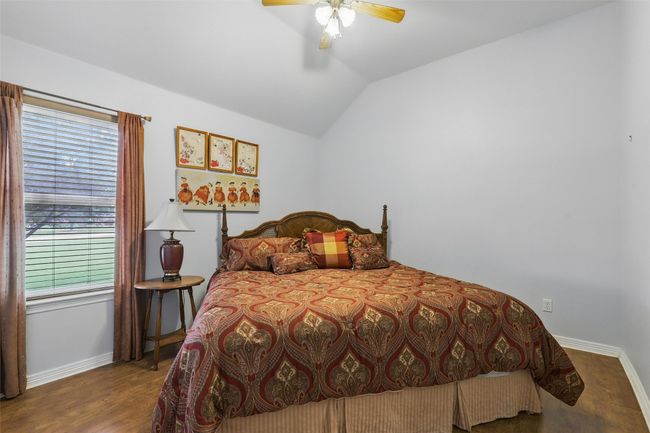 Bedroom featuring vaulted ceiling, wood finished floors, and ceiling fan | Image 23