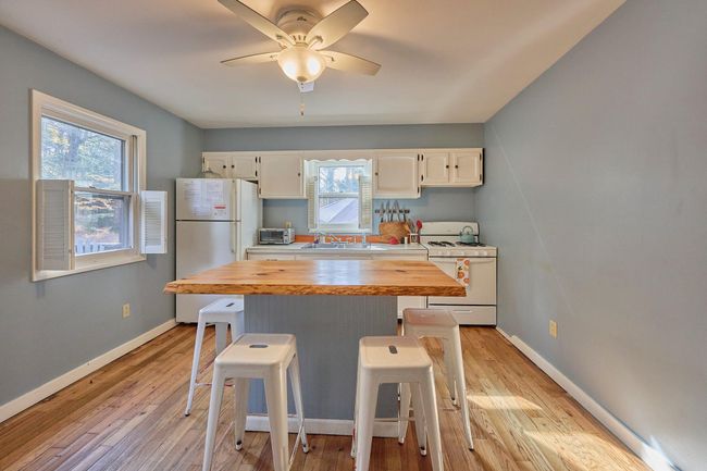 Kitchen with a sink, white cabinetry, a breakfast bar, butcher block counters, and white appliances | Image 21