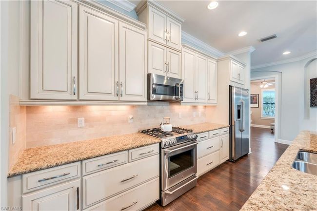 Kitchen featuring appliances with stainless steel finishes, crown molding, dark wood-type flooring, decorative backsplash, and recessed lighting | Image 7
