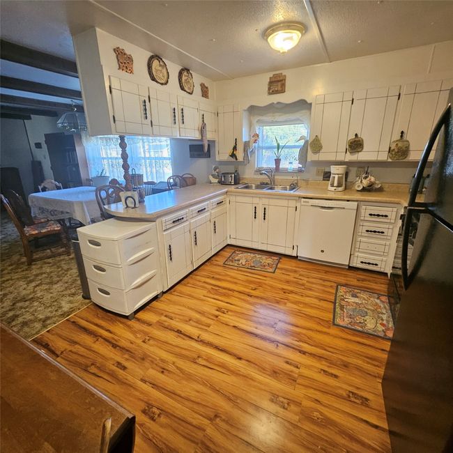 Kitchen featuring white dishwasher, sink, white cabinetry, and light hardwood / wood-style flooring | Image 7
