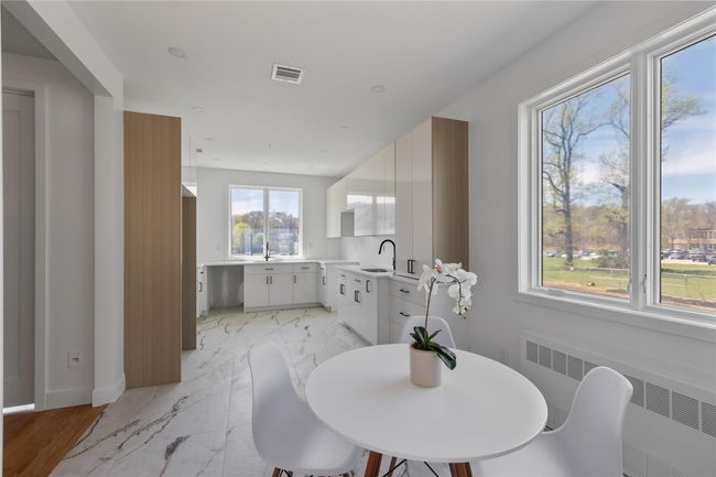 Dining space featuring marble finish floor, baseboards, radiator heating unit, and visible vents | Image 13