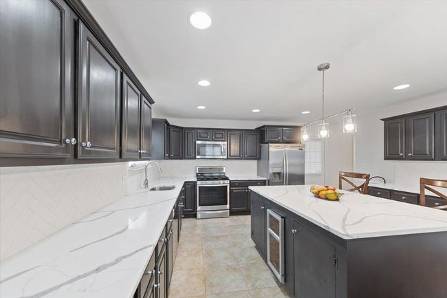 Kitchen featuring decorative backsplash, stainless steel appliances, a kitchen island, and a sink | Image 35