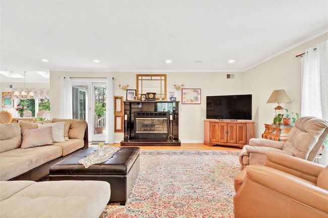 Living room with a chandelier, wood finished floors, recessed lighting, crown molding, and a glass covered fireplace | Image 11
