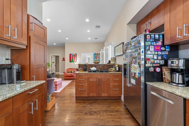 Kitchen featuring brown cabinets, recessed lighting, appliances with stainless steel finishes, light stone counters, and dark wood-style floors | Image 7