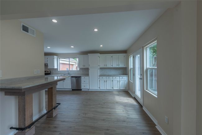 Kitchen with dishwasher, a sink, white cabinetry, decorative backsplash, and light wood finished floors | Image 7