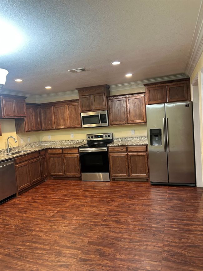 Kitchen featuring crown molding, fridge, range, recessed lighting, and light stone countertops | Image 5