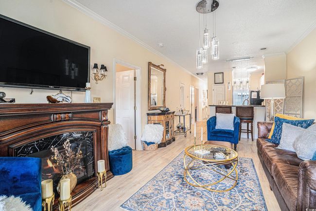 Living area featuring crown molding, light wood-type flooring, a premium fireplace, and a textured ceiling | Image 5
