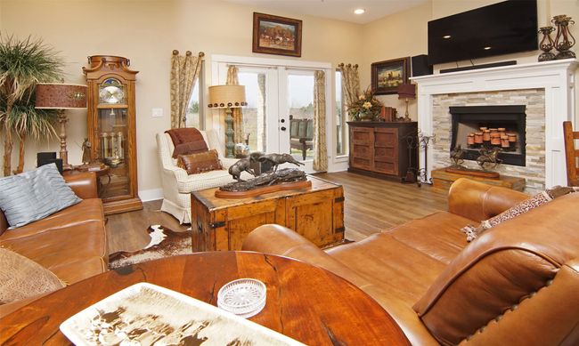 Living area with wood finished floors, french doors, and a stone fireplace | Image 5