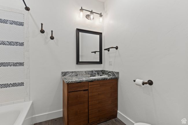 Full bathroom featuring baseboards, wood finished floors, vanity, and bathtub / shower combination | Image 23