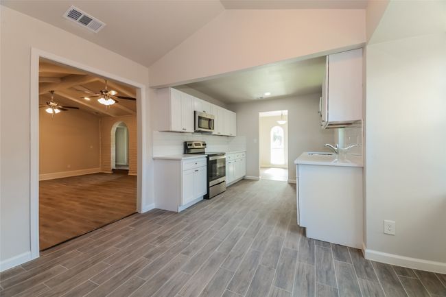 Kitchen with vaulted ceiling, arched walkways, stainless steel appliances, wood finished floors, and light countertops | Image 10