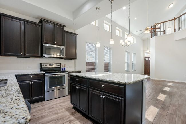 Kitchen with decorative light fixtures, ceiling fan, stainless steel appliances, and light wood finished floors | Image 8