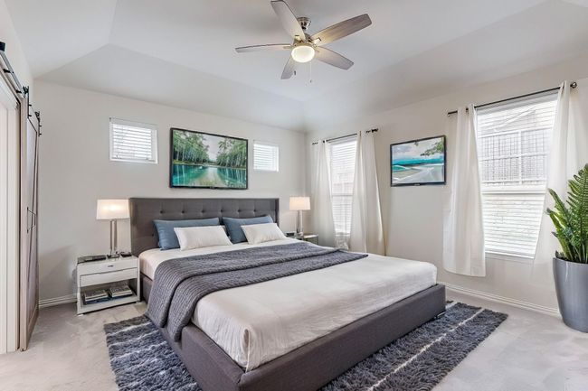 Bedroom featuring a barn door, baseboards, and light carpet | Image 5