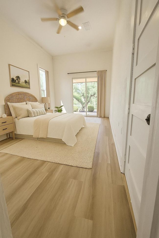 Bedroom featuring light wood-style flooring, multiple windows, and a ceiling fan (AI staged) | Image 8