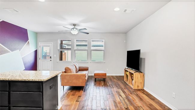Living room with wood-type flooring, baseboards, ceiling fan, and visible vents | Image 7