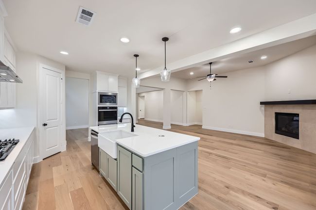 Kitchen featuring visible vents, a fireplace, stainless steel appliances, a ceiling fan, and a sink | Image 10