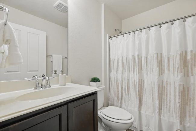 Full Guest bath featuring shower / bath combo with shower curtain, visible vents, vanity, and toilet | Image 23