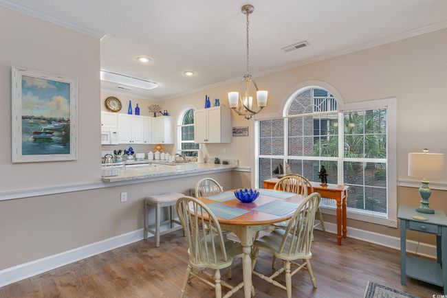 Dining room with a textured ceiling, light hardwood / wood-style flooring, ornamental molding, and a notable chandelier | Image 6