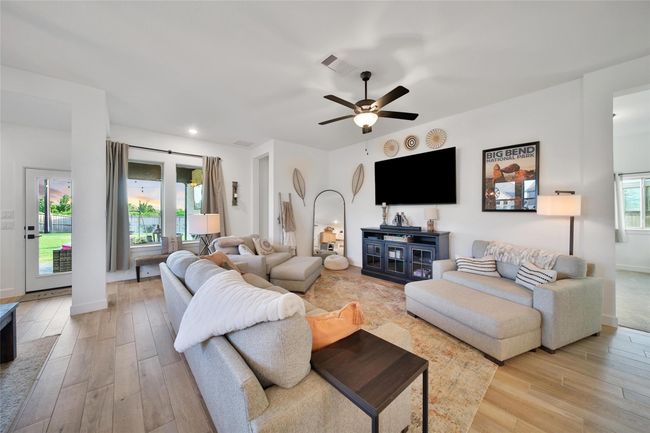 This inviting living room features modern decor with neutral tones, a cozy sectional sofa, and a stylish ceiling fan. It offers ample natural light through large windows and access to an outdoor patio. The space is ideal for relaxing or entertaining. | Image 26