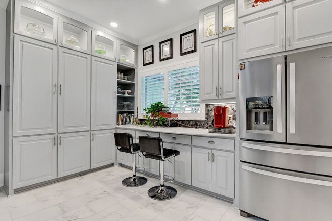 Kitchen with stainless steel refrigerator with ice dispenser, light marble finish flooring, recessed lighting, light countertops, and white cabinets | Image 15