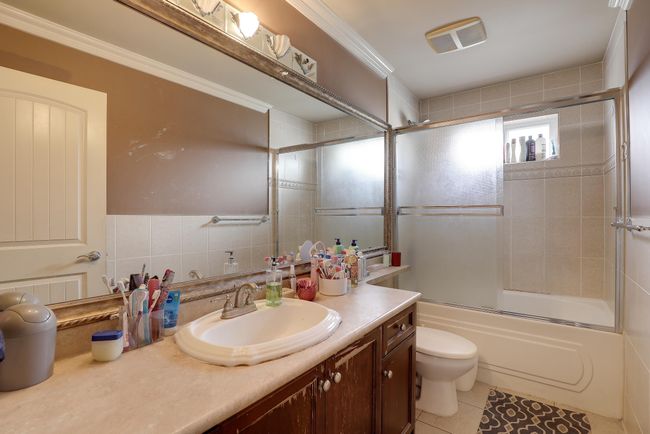 Full bath featuring vanity, toilet, visible vents, enclosed tub / shower combo, and tile patterned flooring | Image 22