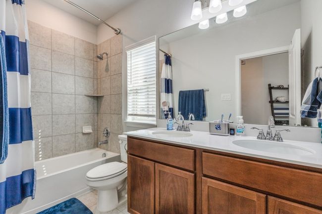 Bathroom with toilet, shower / bathtub combination with curtain, tile patterned flooring, and double vanity | Image 21