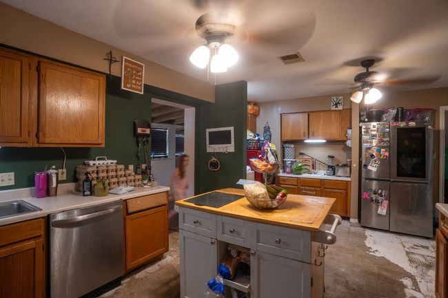 Kitchen featuring appliances with stainless steel finishes, a ceiling fan, butcher block countertops, and brown cabinets | Image 10