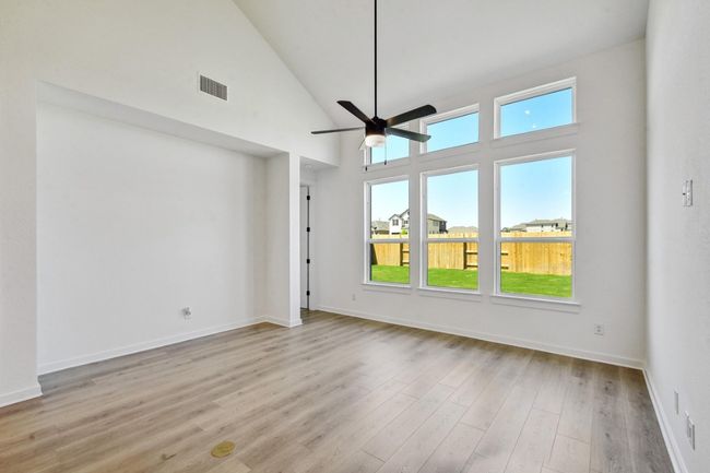 Unfurnished living room featuring high vaulted ceiling, light wood-style flooring, and a ceiling fan | Image 9