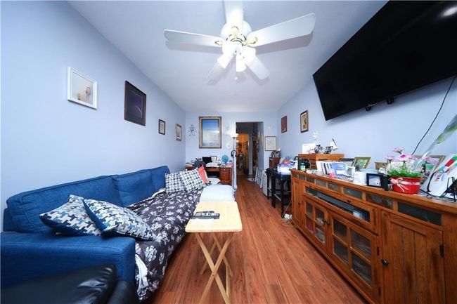 Living area with light wood finished floors and a ceiling fan | Image 9