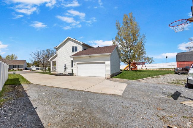 View of home's exterior with a playground, fence, concrete driveway, a lawn, and a garage | Image 5