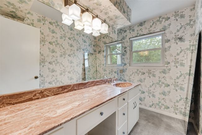Bathroom with vanity, wallpapered walls, baseboards, and a shower | Image 25