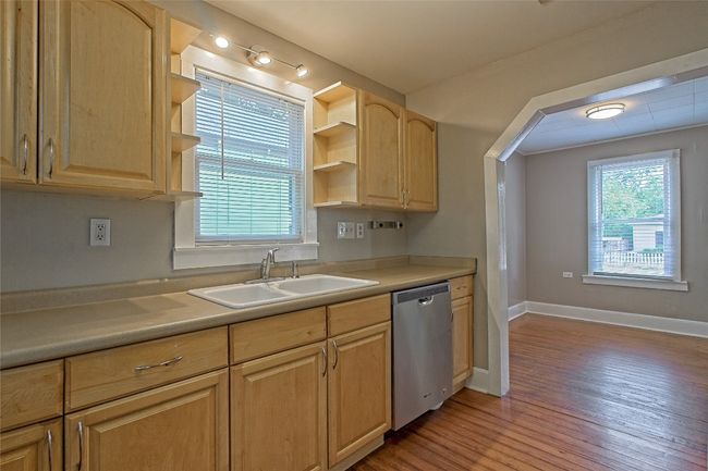 Kitchen featuring stainless steel dishwasher, open shelves, light brown cabinets, light wood-style flooring, and light countertops | Image 15
