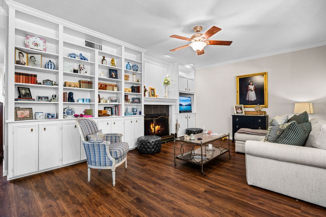 Living area featuring dark wood-style flooring, a ceiling fan, ornamental molding, and a fireplace | Image 8