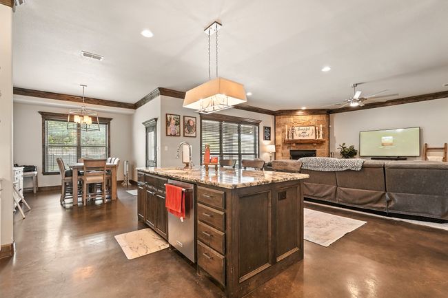 Kitchen with concrete flooring, dishwasher, a fireplace, dark brown cabinetry, and recessed lighting | Image 8