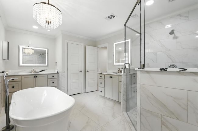 Full bath with a chandelier, a marble finish shower, vanity, crown molding, and a freestanding tub | Image 24