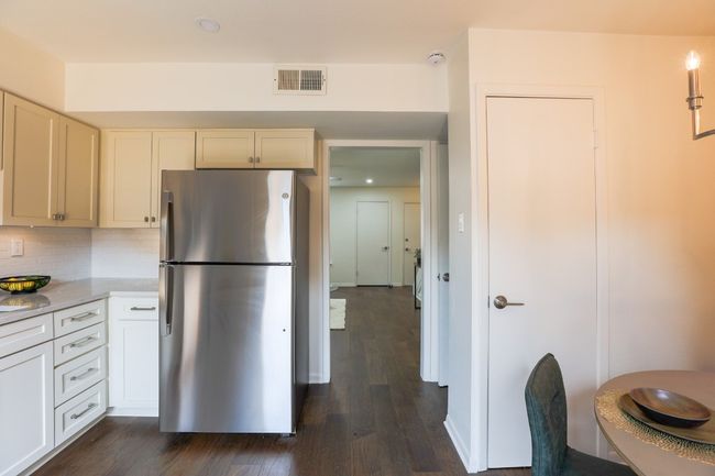 Kitchen with freestanding refrigerator, dark engineered hardwood flooring, tasteful backsplash, light stone quartz counters, and recessed lighting. | Image 11