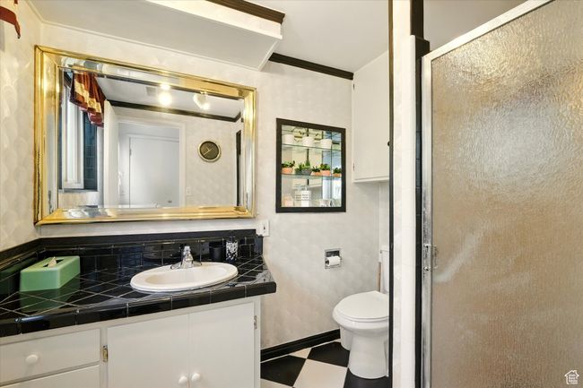Bathroom featuring tile patterned floors, vanity, a stall shower, toilet, and crown molding | Image 17