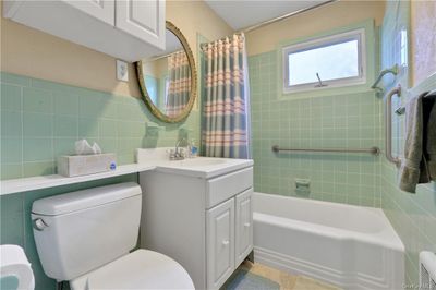 Full bathroom with tile walls, toilet, shower / tub combo, and vanity | Image 3