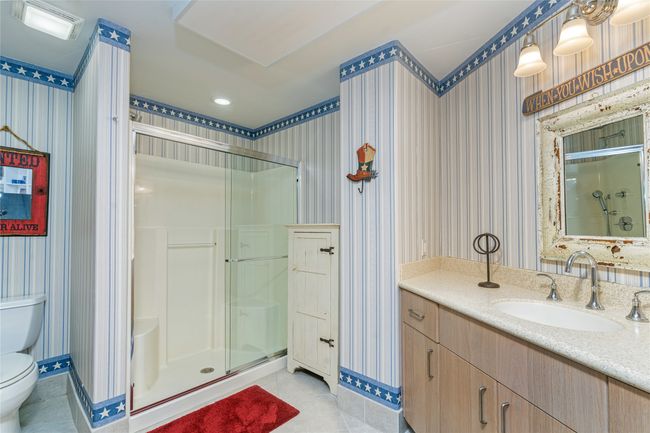 Bathroom with an enclosed shower, vanity, tile patterned floors, and toilet | Image 36