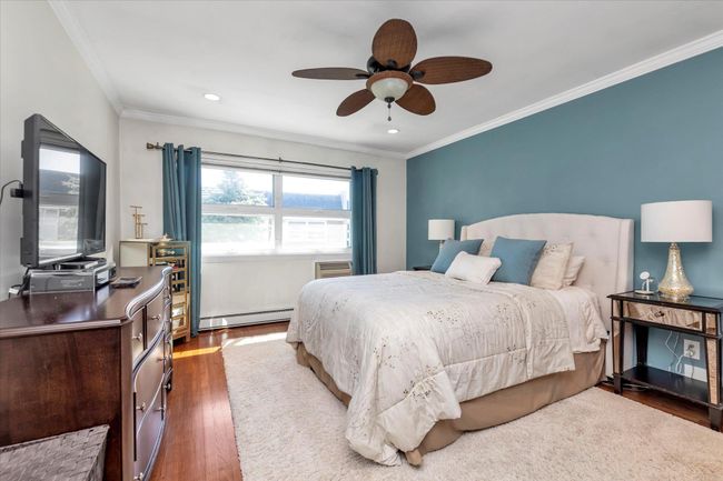 Bedroom featuring crown molding, a ceiling fan, wood finished floors, a baseboard heating unit, and recessed lighting | Image 7