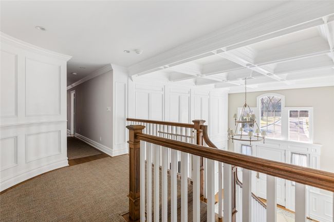 Corridor with dark wood finished floors, ornamental molding, an upstairs landing, beam ceiling, and a notable chandelier | Image 27