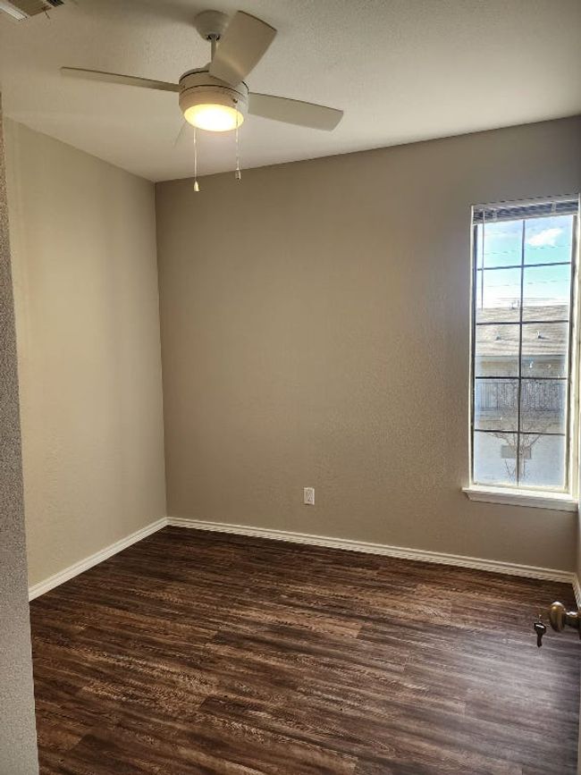 Spare room featuring dark wood finished floors, baseboards, visible vents, and a ceiling fan | Image 6