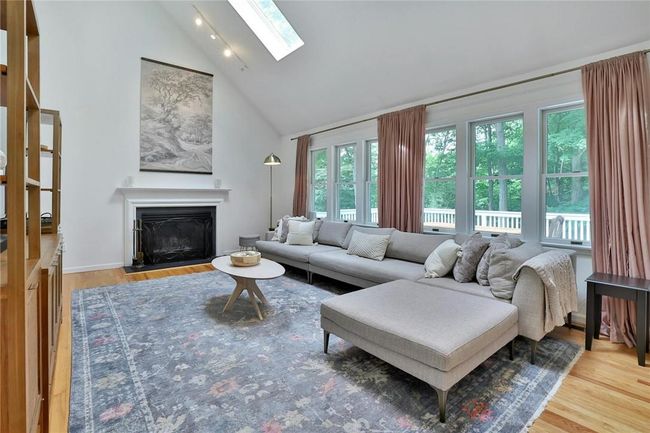 The eat in area flows to the gorgeous family room with skylights, a wall of windows, and wood burning fireplace. The enormous deck is visible through the windows and endless greenery makes it feel like a treehouse. | Image 12