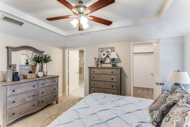 Bedroom featuring light colored carpet, a walk in closet, a closet, ensuite bath, and a tray ceiling | Image 19