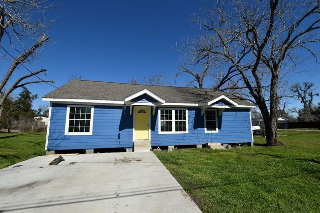 Charming blue house with a covered back porch, set in a spacious yard with mature trees. Ideal for outdoor activities and relaxation in a serene setting. | Image 21