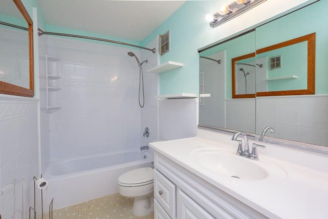 Bathroom featuring vanity, shower / bath combination, tile walls, and tile patterned floors | Image 11