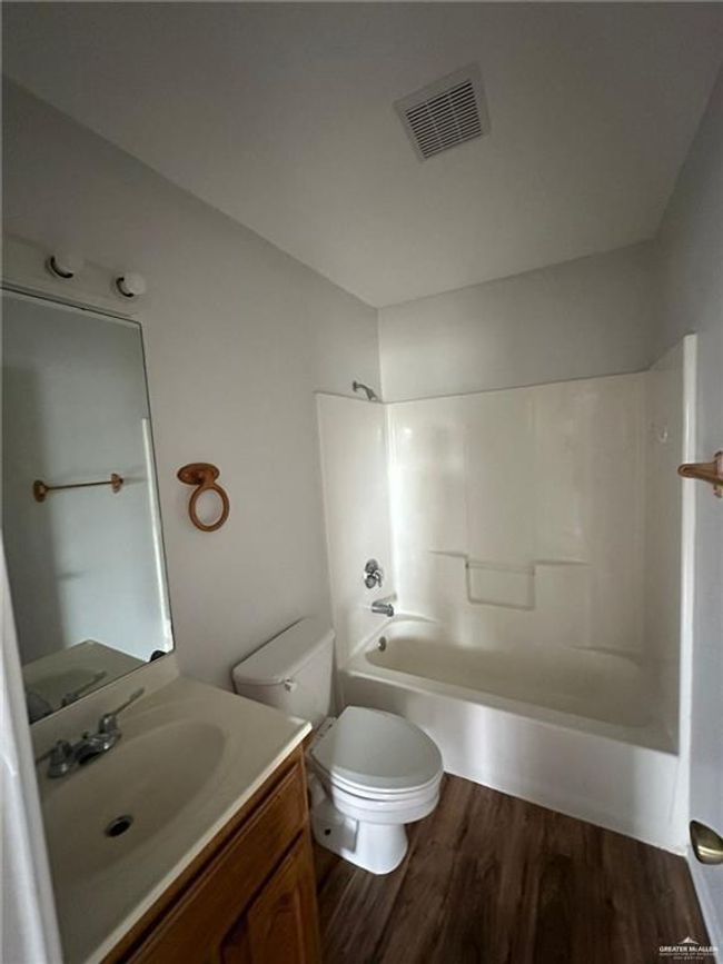 Full bathroom with vanity, wood finished floors, visible vents, shower / bath combination, and toilet | Image 7