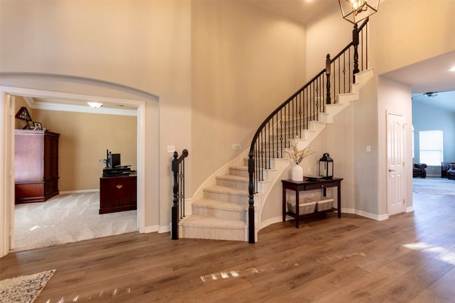 Stairs with a high ceiling, wood finished floors, and arched walkways | Image 4